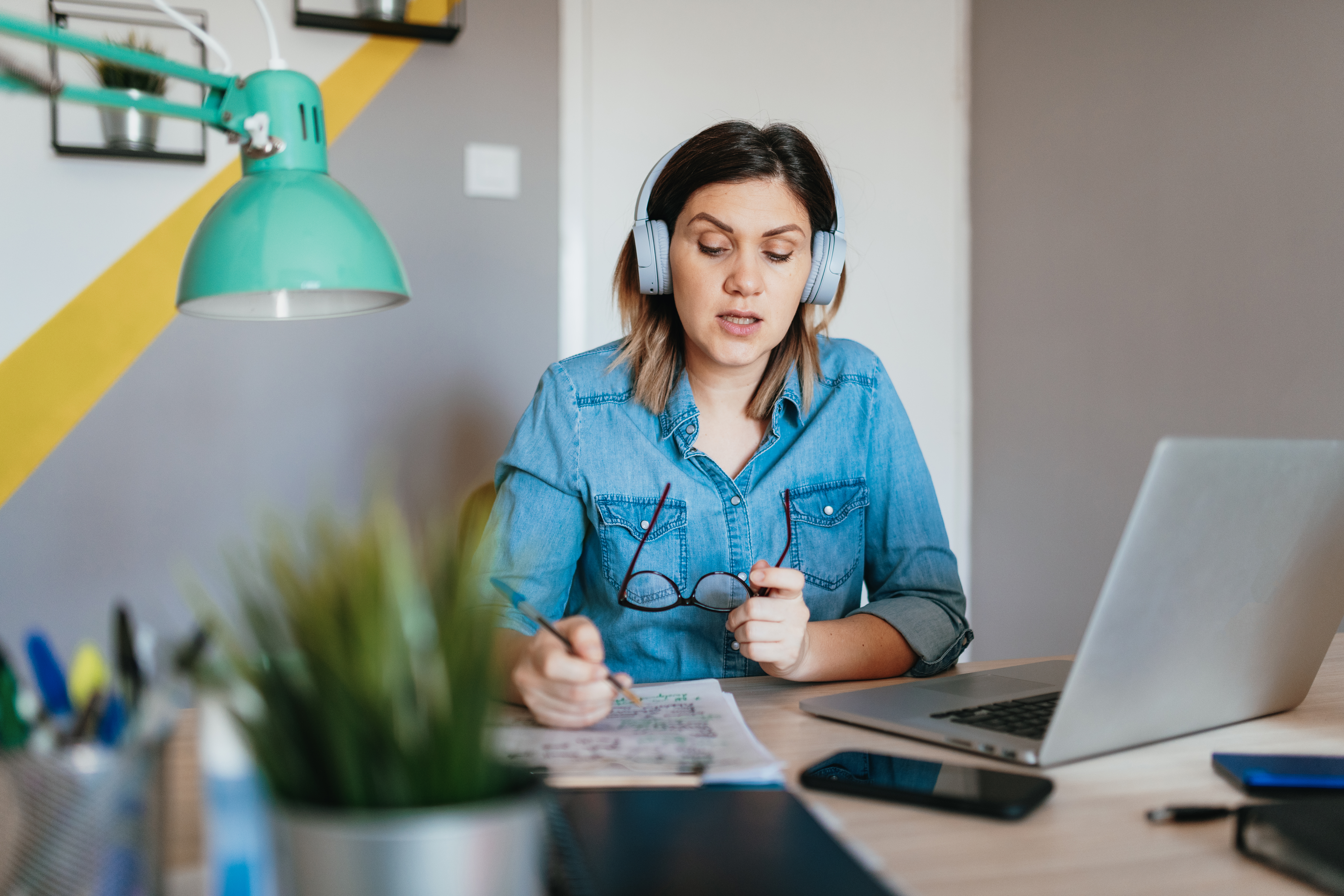 Woman working from home in a conference call while talking notes